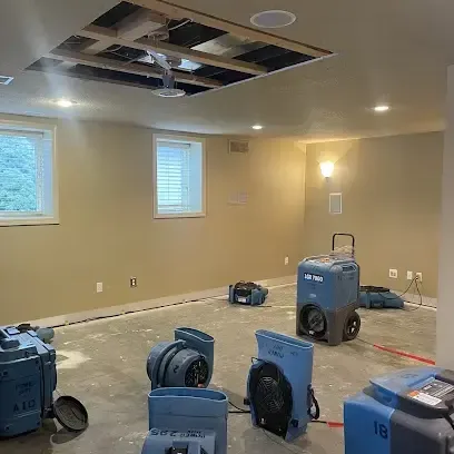 Dehumidifiers and air movers drying a finished basement with part of the ceiling opened