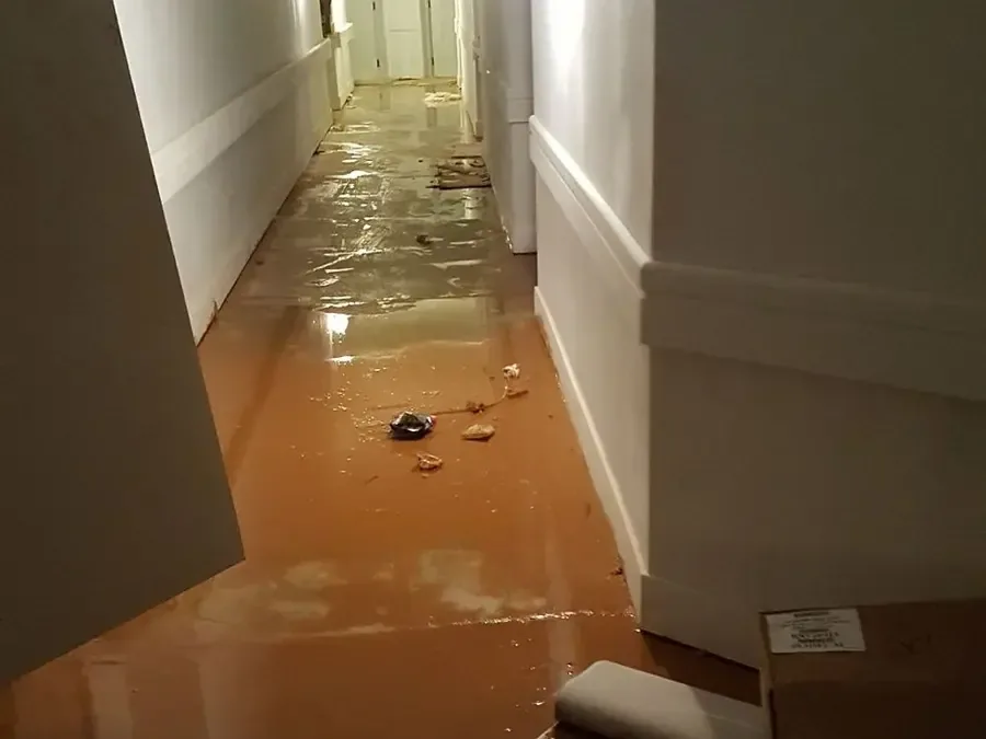 Muddy floodwater and debris covering a hallway floor