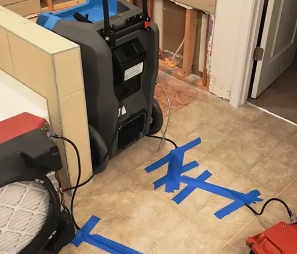 Air movers and a dehumidifier aimed at a flood-cut wall