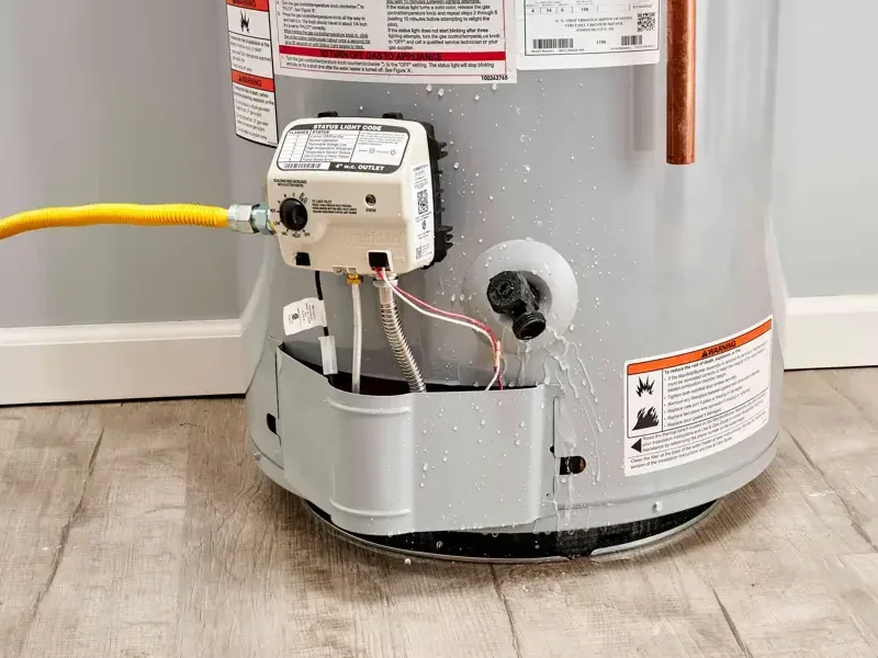 Water leaking out from the base of a tank water heater onto the floor